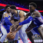 
              Brooklyn Nets' Ben Simmons, center, tries to keep the ball away from Philadelphia 76ers' Tobias Harris, left, and Paul Reed during the second half of an NBA basketball game, Tuesday, Nov. 22, 2022, in Philadelphia. (AP Photo/Matt Slocum)
            