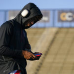
              Los Alamitos High School quarterback Malachi Nelson looks at his phone while warming up before a high school football game against Newport Harbor High School on Friday, Sept. 30, 2022, in Newport Beach, Calif. (AP Photo/Ashley Landis)
            