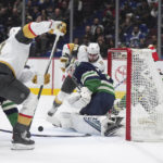 
              Vancouver Canucks goalie Thatcher Demko, center front, stops Vegas Golden Knights' Brett Howden (21), front left, during first-period NHL hockey game action in Vancouver, British Columbia, Monday, Nov. 21, 2022. (Darryl Dyck/The Canadian Press via AP)
            
