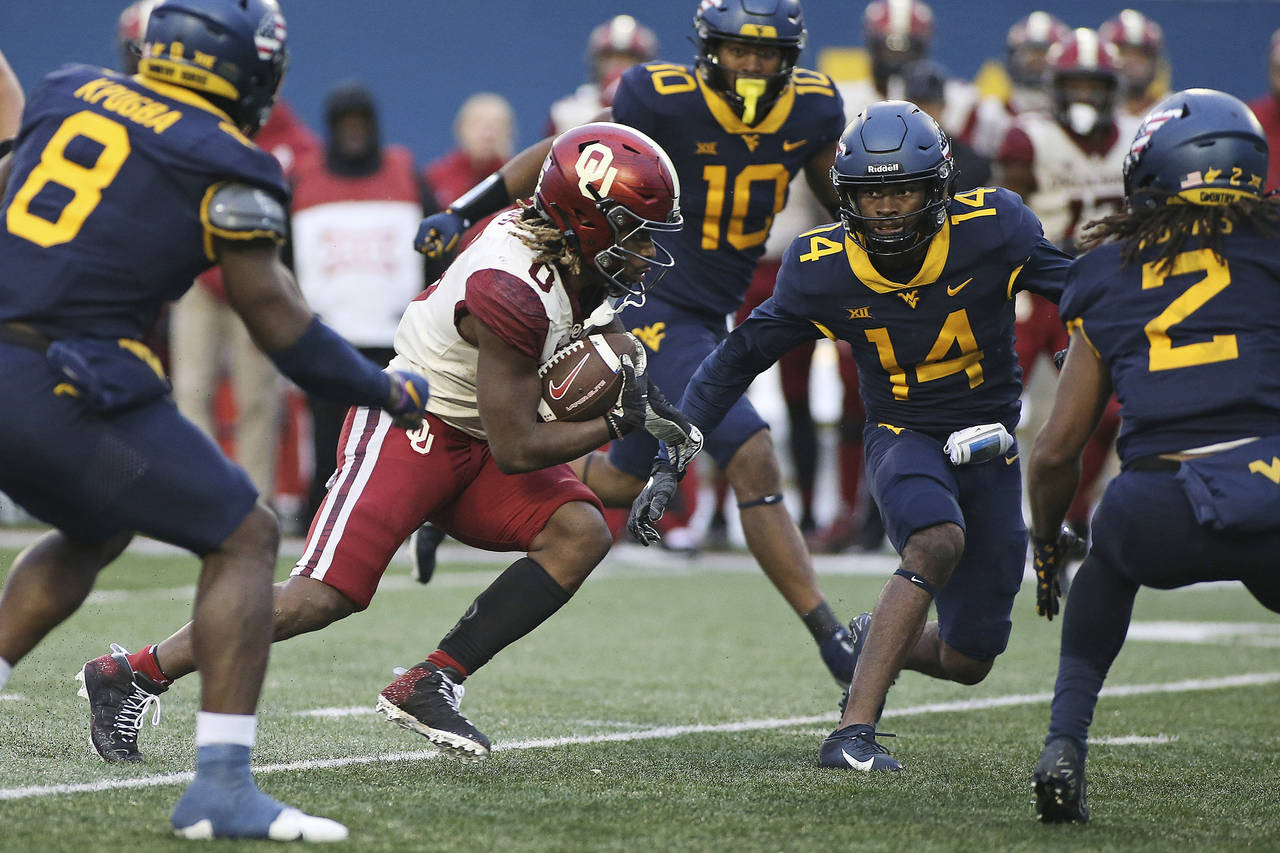 Oklahoma running back Eric Gray (0) is defended by West Virginia safety Malachi Ruffin (14) during ...