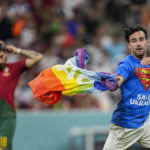 
              A pitch invader runs across the field with a rainbow flag during the World Cup group H soccer match between Portugal and Uruguay, at the Lusail Stadium in Lusail, Qatar, Monday, Nov. 28, 2022. (AP Photo/Abbie Parr)
            
