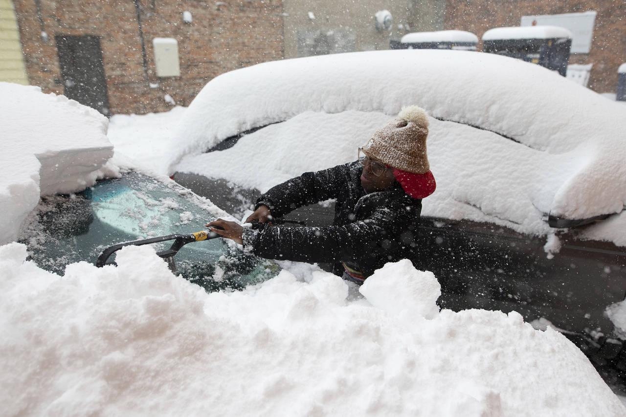 Zaria Black, 24, from Buffalo, clears off her car as snow falls Friday, Nov. 18, 2022, in Buffalo, ...