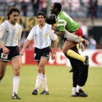 
              FILE - Dejected Argentine players Nestor Gabriel Lorenzo, left, and Jorge Luis Burruchaga walk off the pitch, past unidentified celebrating Cameroon players, after the opening match of the soccer World Cup, in Milan, Italy on June 8, 1990. The World Cup has produced its fair share of shocks, not least when Cameroon defeated defending champion Argentina 1-0 in 1990. (AP Photo/File)
            
