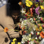 
              A person places a flower on a memorial before a memorial service in Charlottesville, Va., Saturday, Nov. 19, 2022. Over a thousand students and locals attended the service at John Paul Jones Arena to honor three student football players who were killed on Sunday, Nov. 13, 2022. (Mike Kropf/The Daily Progress via AP)
            