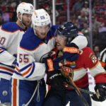 
              Edmonton Oilers left wing Dylan Holloway (55) wraps his arm around Florida Panthers left wing Ryan Lomberg (94) during the second period of an NHL hockey game, Saturday, Nov. 12, 2022, in Sunrise, Fla. (AP Photo/Lynne Sladky)
            