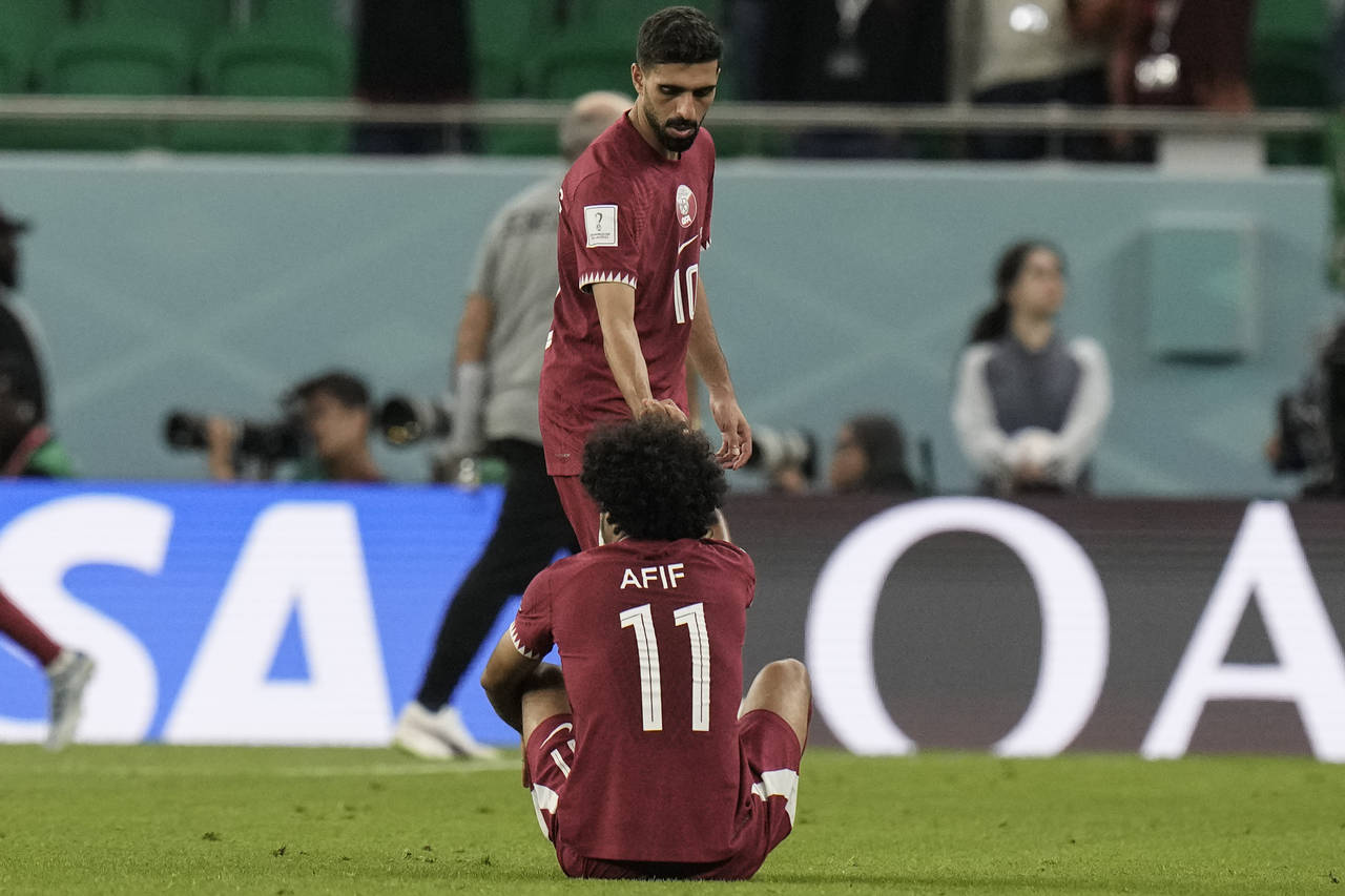 Qatar's Hassan Al-Haydos helps Akram Afif stand up after the World Cup group A soccer match between...