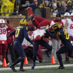
              Nebraska wide receiver Alante Brown (4) is upended by Michigan defensive back Mike Sainristil (0) as DJ Turner (5) looks on in the first half of an NCAA college football game in Ann Arbor, Mich., Saturday, Nov. 12, 2022. (AP Photo/Paul Sancya)
            