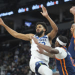 
              Minnesota Timberwolves center Karl-Anthony Towns, left, passes the ball while defended by New York Knicks forward Cam Reddish (0) and center Jericho Sims, right, during the first half of an NBA basketball game, Monday, Nov. 7, 2022, in Minneapolis. (AP Photo/Abbie Parr)
            