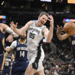 
              San Antonio Spurs' Jakob Poeltl (25) and New Orleans Pelicans' Herbert Jones (5) fight for possession as New Orleans' Jonas Valanciunas (17) watches during the first half of an NBA basketball game, Wednesday, Nov. 23, 2022, in San Antonio. (AP Photo/Darren Abate)
            