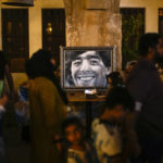 
              People walk past a painting of Argentinian soccer idol Diego Armando Maradona in a pedestrian area in downtown Doha, Qatar, Friday, Nov. 18, 2022. (AP Photo/Francisco Seco)
            