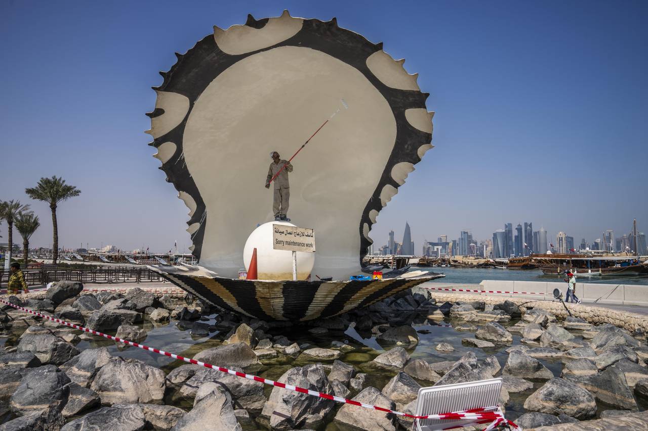 A migrant laborer paints The Pearl Monument, a sculpture depicting an open oyster shell with runnin...