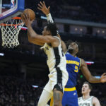 
              San Antonio Spurs guard Devin Vassell, center left, shoots while defended by Golden State Warriors center Kevon Looney (5) during the first half of an NBA basketball game in San Francisco, Monday, Nov. 14, 2022. (AP Photo/Godofredo A. Vásquez)
            