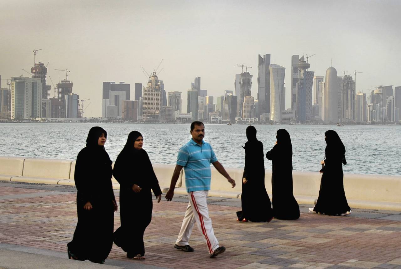 FILE- Qatari women and a man walk in front of the city skyline in Doha, Qatar, Saturday, April 7, 2...