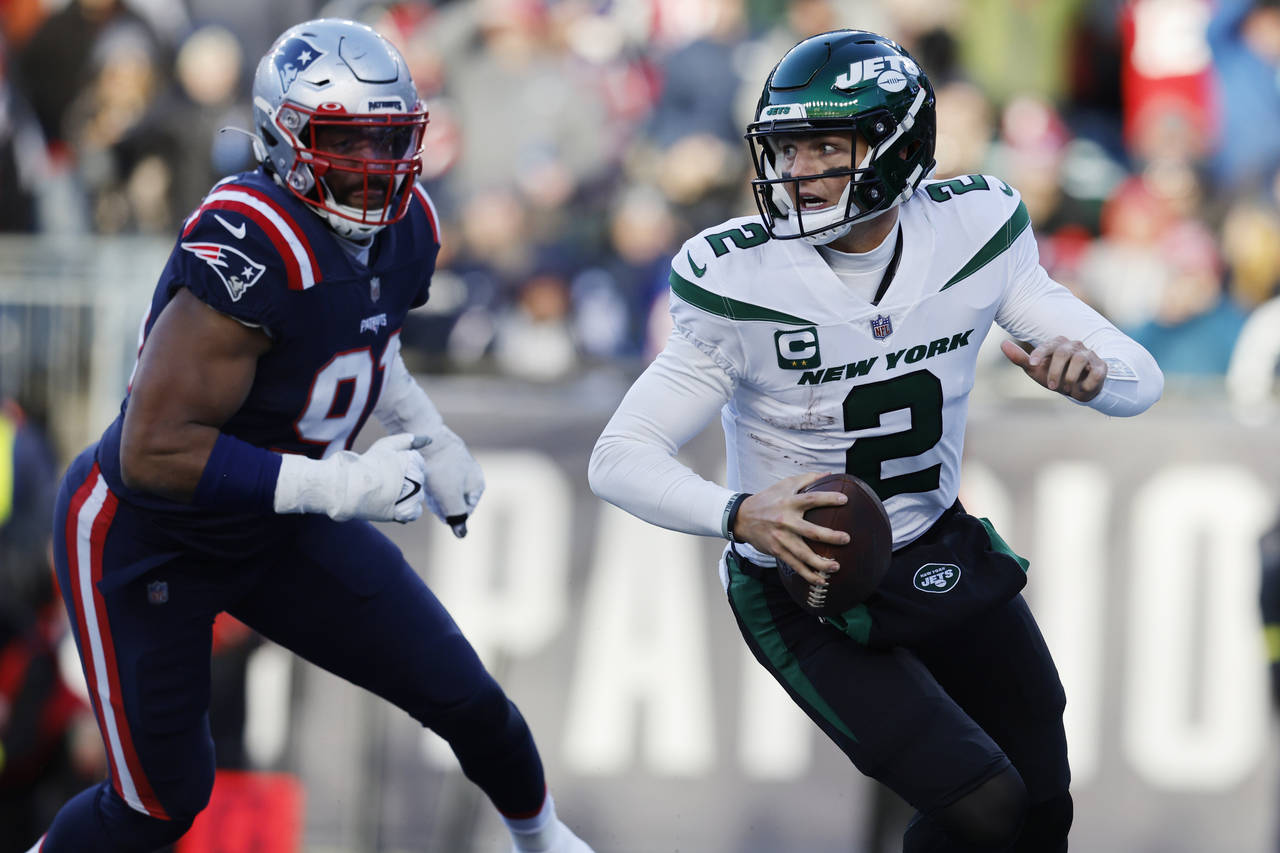 New York Jets quarterback Zach Wilson (2) runs as New England Patriots defensive end Deatrich Wise ...