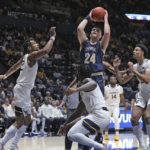 
              Mount St. Mary's forward Frantisek Barton (24) shoots over West Virginia forward Josiah Harris, left, guard Joe Toussaint, front, and forward Tre Mitchell, right, during the first half of an NCAA college basketball game in Morgantown, W.Va., Monday, Nov. 7, 2022. (AP Photo/Kathleen Batten)
            