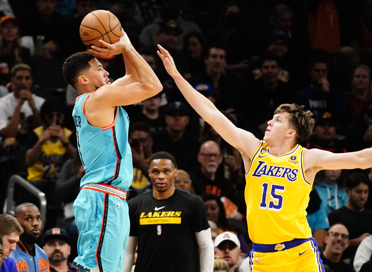 Phoenix Suns' Devin Booker shoots a three pointer against Los Angeles Lakers' Austin Reaves (15) du...