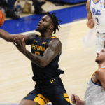 
              West Virginia's Joe Toussaint, left, scores past Pittsburgh's Nate Santos during the second half of an NCAA college basketball game, Friday, Nov. 11, 2022, in Pittsburgh. (AP Photo/Keith Srakocic)
            