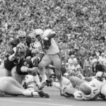 
              FILE - Ohio State's Archie Griffin picks up some of his game-high 163 yards against Michigan during an NCAA college football game in Ann Arbor, Mich., as Michigan's Walt Williamson (91), Carl Russ (33) and Steve Strinko (59) defend. The game between the undefeated teams ended in a 10-10 ties. (AP Photo, File)
            