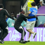 
              A pitch invader runs is caught while running across the field with a rainbow flag during the World Cup group H soccer match between Portugal and Uruguay, at the Lusail Stadium in Lusail, Qatar, Monday, Nov. 28, 2022. (AP Photo/Petr David Josek)
            