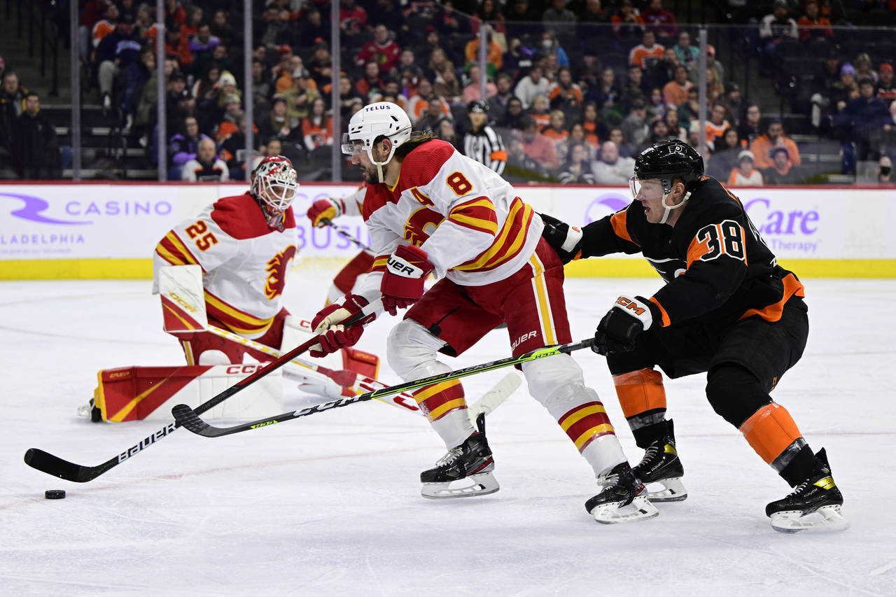 Calgary Flames' Chris Tanev (8) plays a loose puck past Philadelphia Flyers' Patrick Brown (38) dur...