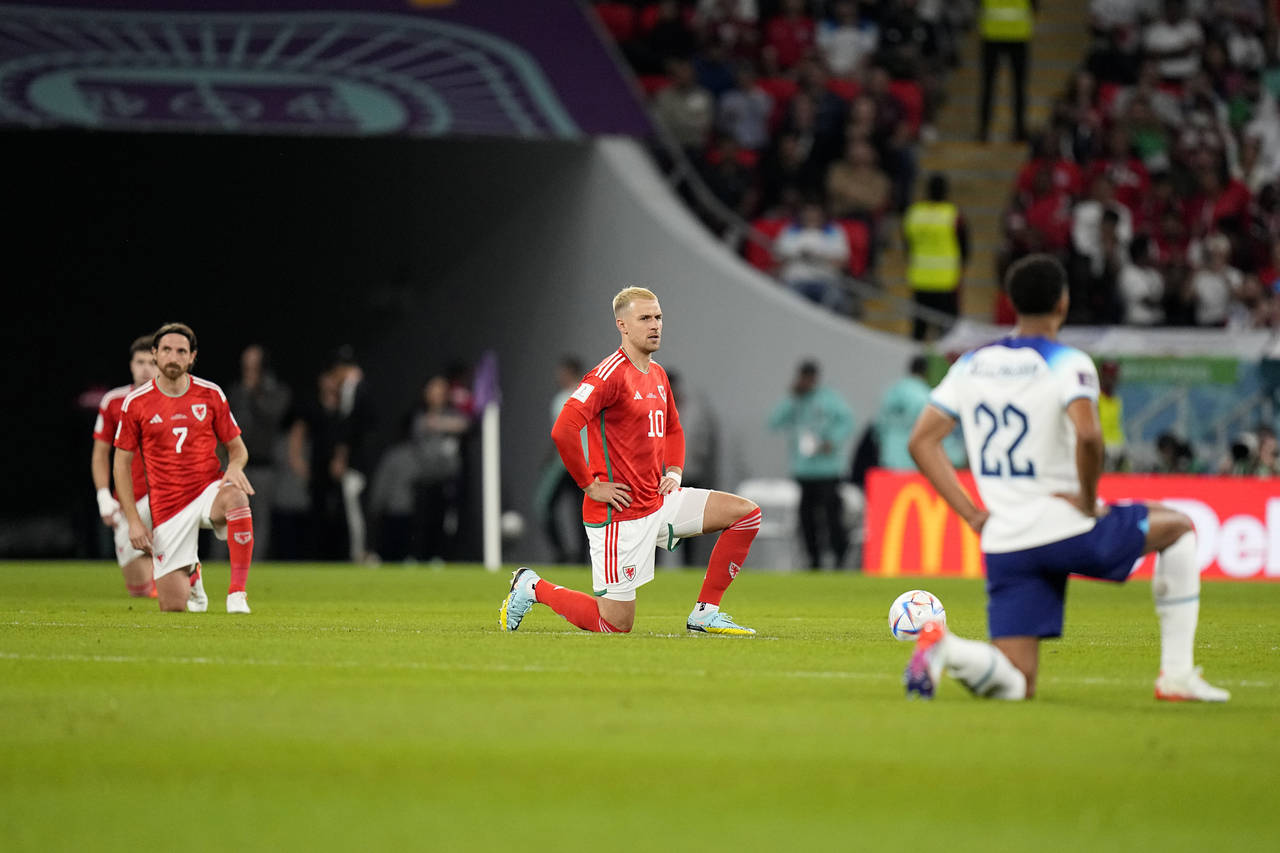 Wales and England players take knee before the start of the World Cup group B soccer match between ...