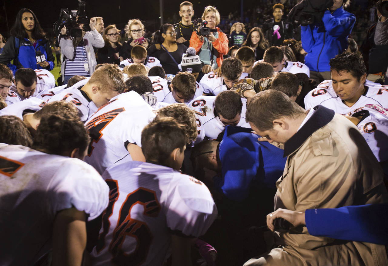 FILE - Bremerton High School assistant football coach Joe Kennedy, center in blue, kneels and prays...