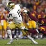 
              Notre Dame quarterback Drew Pyne, left, avoids being sacked by Southern California defensive end Korey Foreman during the first half of an NCAA college football game Saturday, Nov. 26, 2022, in Los Angeles. (AP Photo/Mark J. Terrill)
            