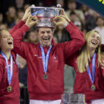 
              Switzerland's players Simona Waltert, Viktorija Golubic, Jil Teichmann and Belinda Bencic, from left, with team captain Heinz Guenthardt in the center, celebrate with the trophy after defeating Australia to win the Billie Jean King Cup tennis finals, at the Emirates Arena in Glasgow, Scotland, Sunday, Nov. 13, 2022. (AP Photo/Kin Cheung)
            