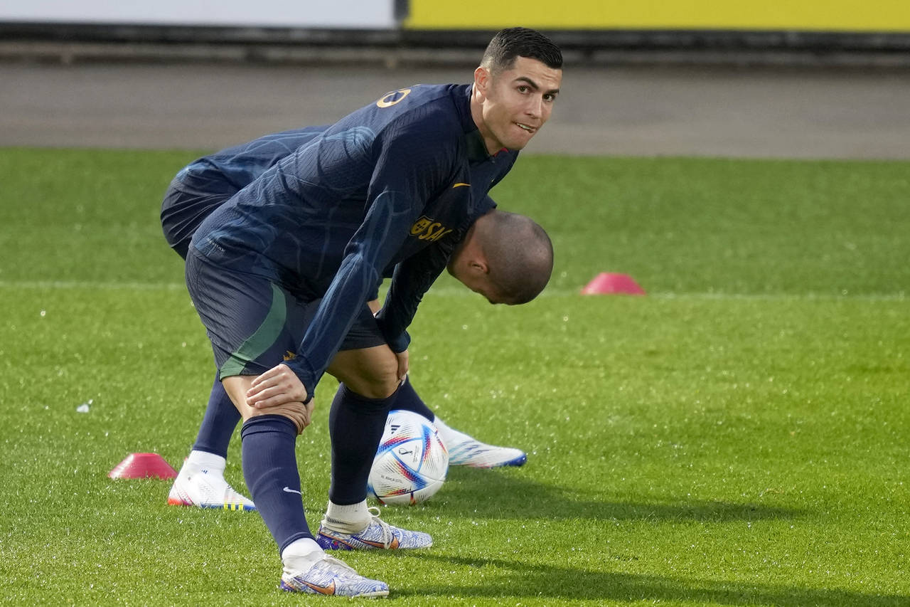 Cristiano Ronaldo stretches with teammate Pepe, in the background, during a Portugal soccer team tr...
