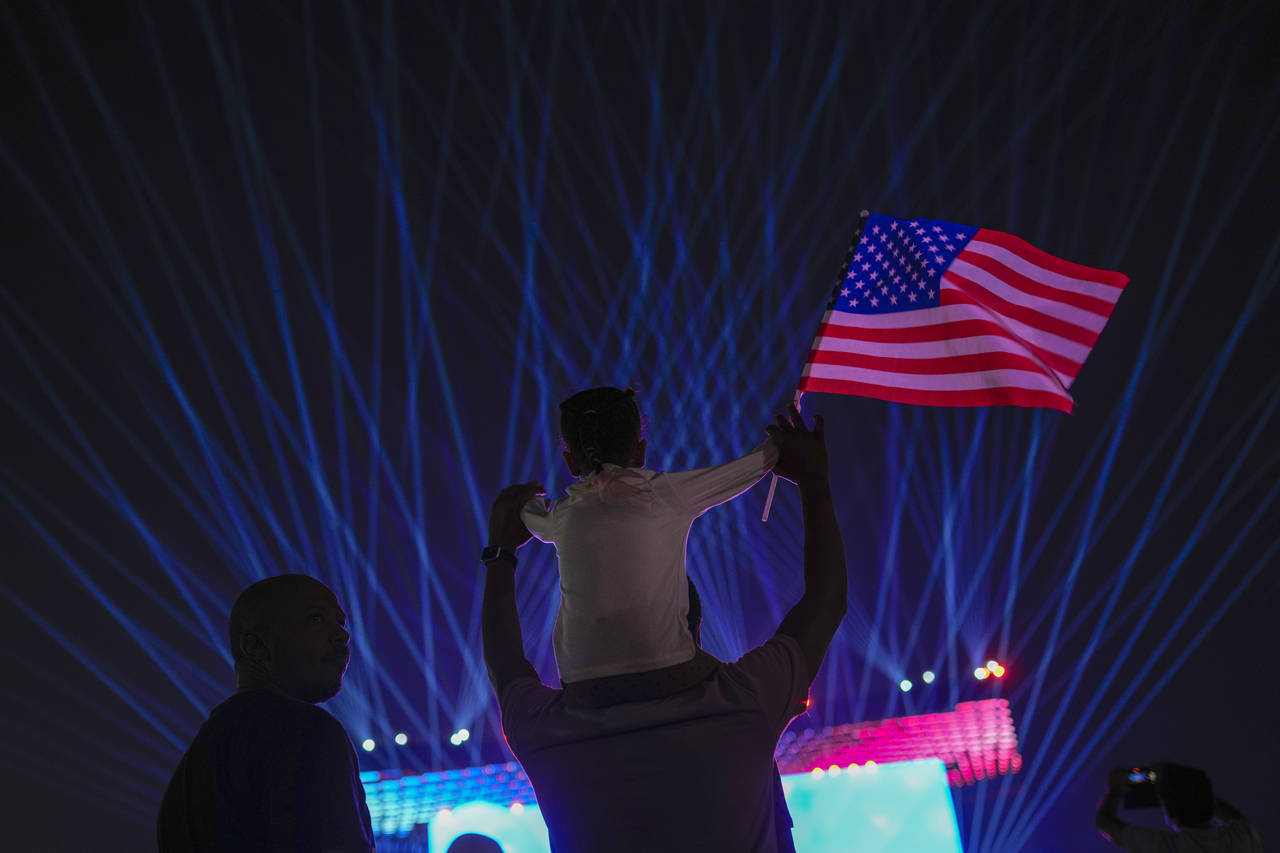 A child waves an US flag as people cheer up in the fan zone prior the opening ceremony of the World...