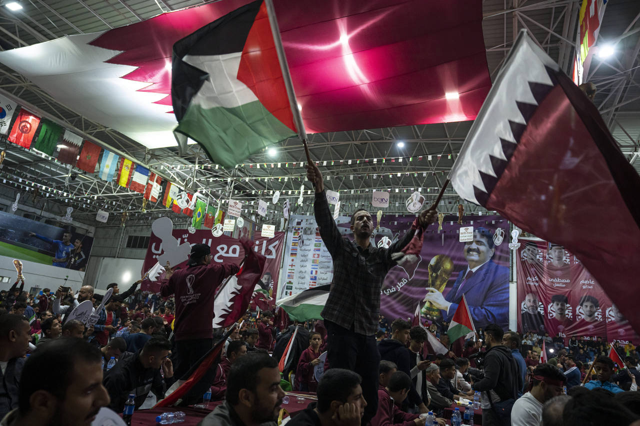FILE - Palestinian soccer fans wave Qatari and Palestinian flags as they watch a live broadcast of ...