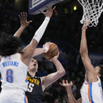 
              Denver Nuggets center Nikola Jokic (15) is fouled by Oklahoma City Thunder forward Jalen Williams (8) as he shoots between Williams and Jeremiah Robinson-Earl, right, during the first half of an NBA basketball game Wednesday, Nov. 23, 2022, in Oklahoma City. (AP Photo/Sue Ogrocki)
            