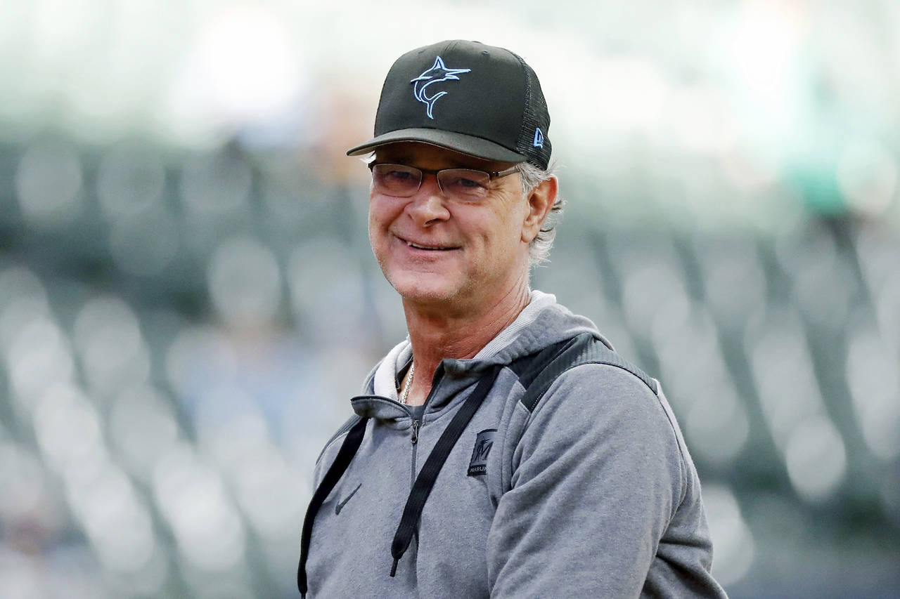 FILE - Then-Miami Marlins manager Don Mattingly smiles after throwing a ball to fans before a baseb...