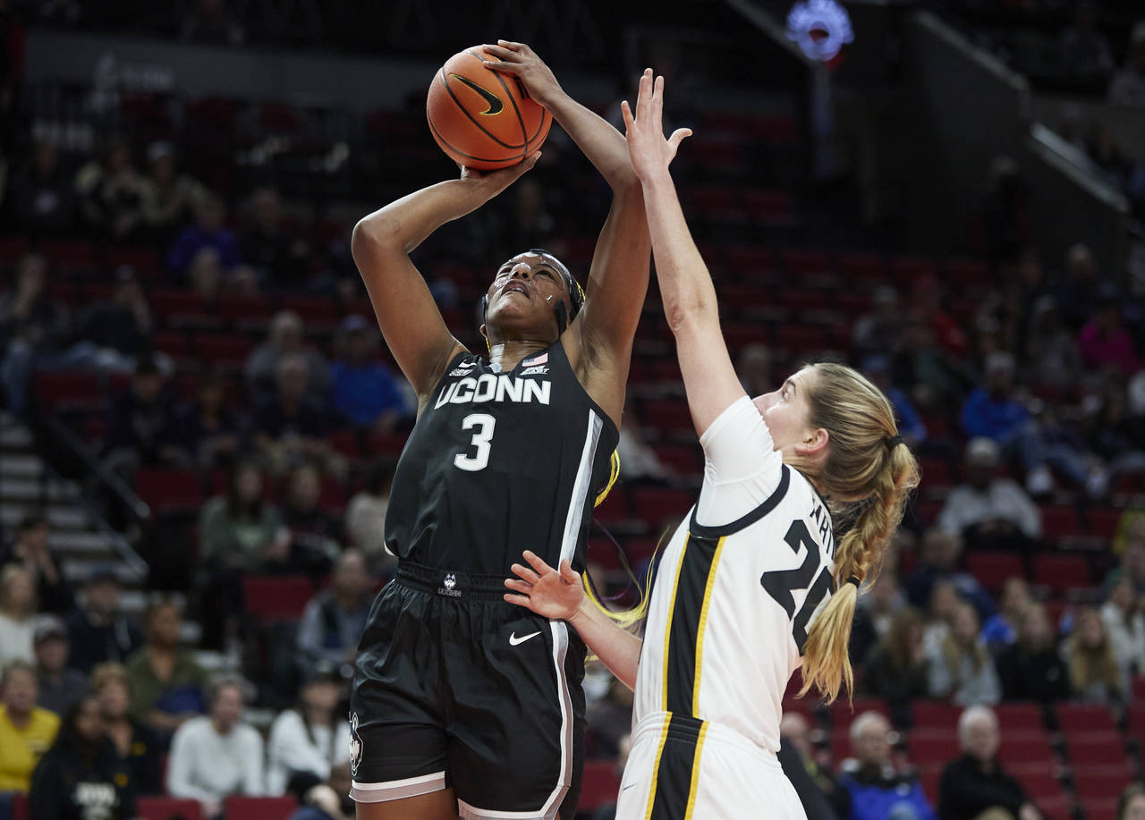 UConn forward Aaliyah Edwards, left, shoots over Iowa guard Kate Martin during the first half of an...
