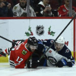 
              Chicago Blackhawks center Jason Dickinson and Winnipeg Jets defenseman Neal Pionk fall on the ice while chasing the puck during the first period of an NHL hockey game, Sunday, Nov. 27, 2022, in Chicago. (AP Photo/Matt Marton)
            