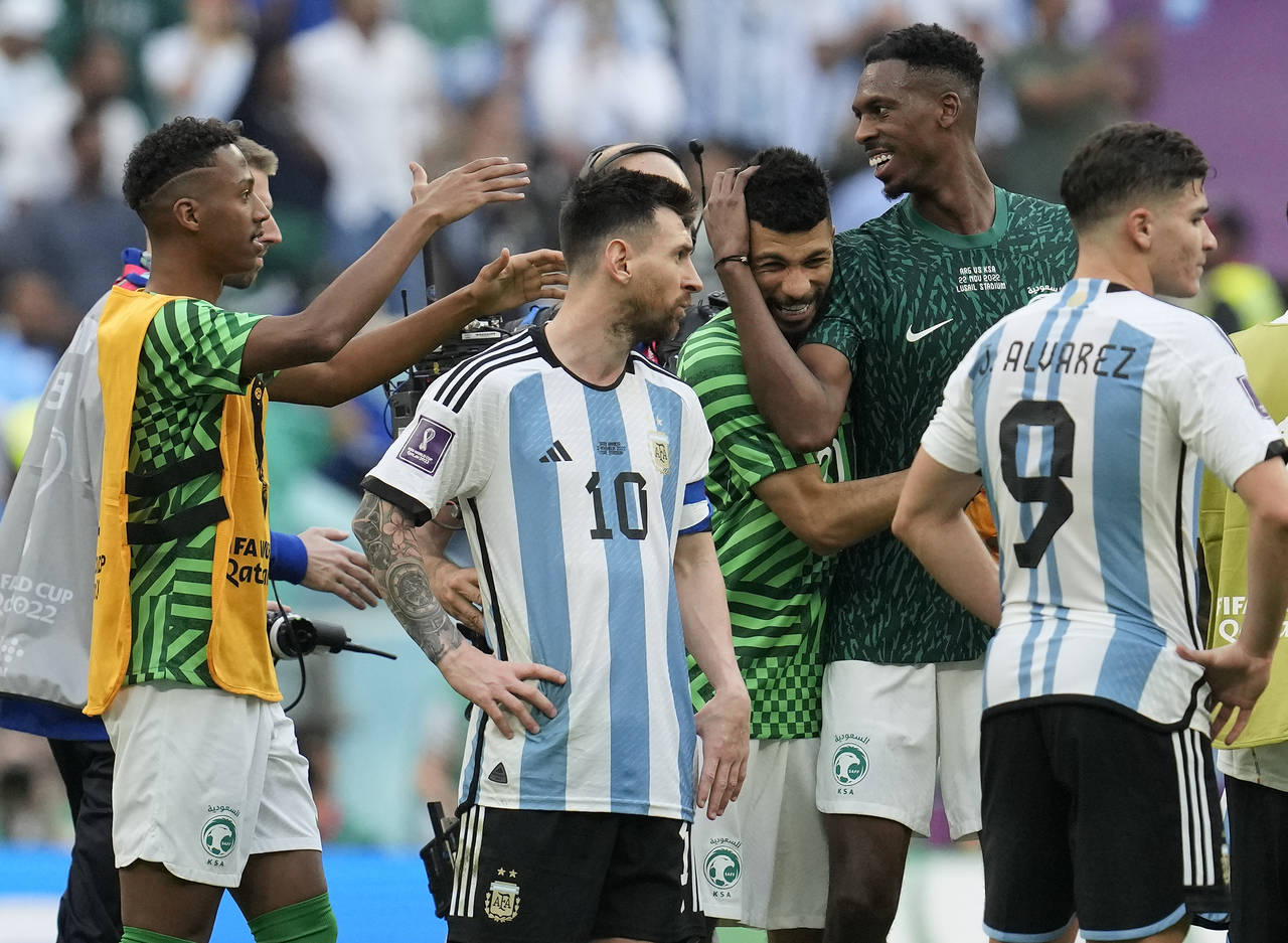 Argentina's Lionel Messi standing beside Saudi Arabia's players celebrating after winning the World...