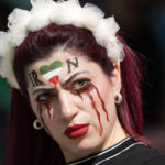 
              A woman stands on the tribune with her face painted in memory of Mahsa Amini, a woman who died while in police custody in Iran at the age of 22, prior to the World Cup group B soccer match between Wales and Iran, at the Ahmad Bin Ali Stadium in Al Rayyan , Qatar, Friday, Nov. 25, 2022. (AP Photo/Frank Augstein)
            