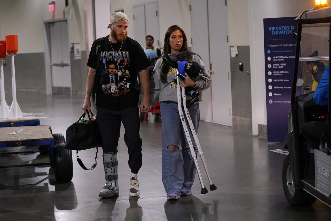 Los Angeles Rams wide receiver Cooper Kupp, left, walks out in street clothes and a boot on his foo...