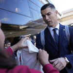 
              Portugal's Cristiano Ronaldo signs a shirt for Giuliana, a fan from Brazil, as he arrives with the Portuguese team at Lisbon airport to depart for the World Cup in Qatar, Friday, Nov. 18, 2022. (AP Photo/Armando Franca)
            