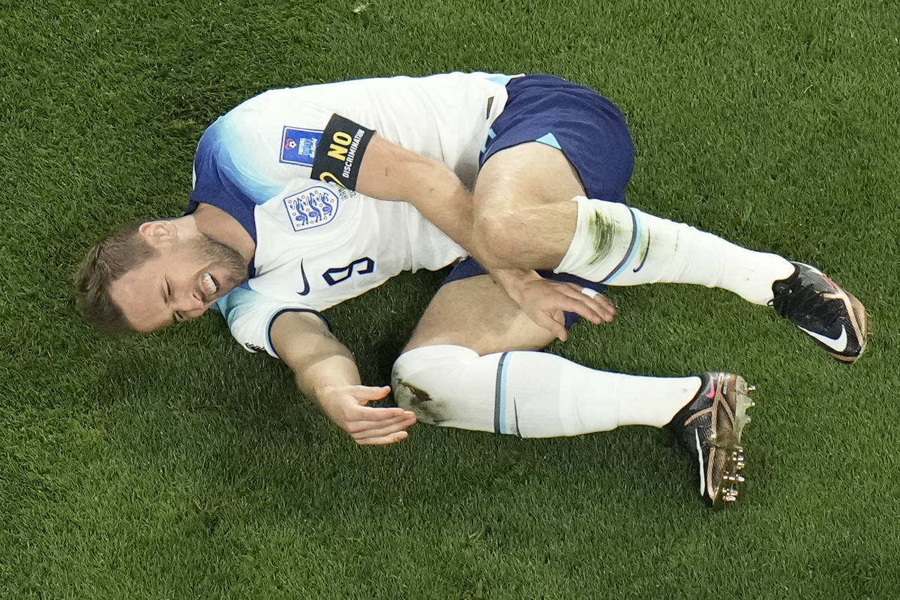 England's Harry Kane grimaces in pain after a tackle by Iran's Morteza Pouraliganji during the Worl...