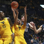 
              West Virginia forwards Jimmy Bell Jr. (15) and Emmitt Matthews Jr. (1) go for a rebound while defended by Penn forwards Nick Spinoso (13) and Max Martz (14) during the first half of an NCAA college basketball game in Morgantown, W.Va., Friday, Nov. 18, 2022. (AP Photo/Kathleen Batten)
            