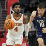 
              Texas guard Tyrese Hunter (4) moves the ball past Northern Arizona forward Jack Wistrcill (10) during the first half of an NCAA college basketball game, Monday, Nov. 21, 2022, in Edinburg, Texas. (AP Photo/Eric Gay)
            