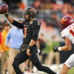 
              Oklahoma State quarterback Spencer Sanders (3) holds up the ball while running out of bounds under pressure from Iowa State defensive back Beau Freyler (17) during the second half of an NCAA college football game Saturday, Nov. 12, 2022, in Stillwater, Okla. (AP Photo/Brody Schmidt)
            