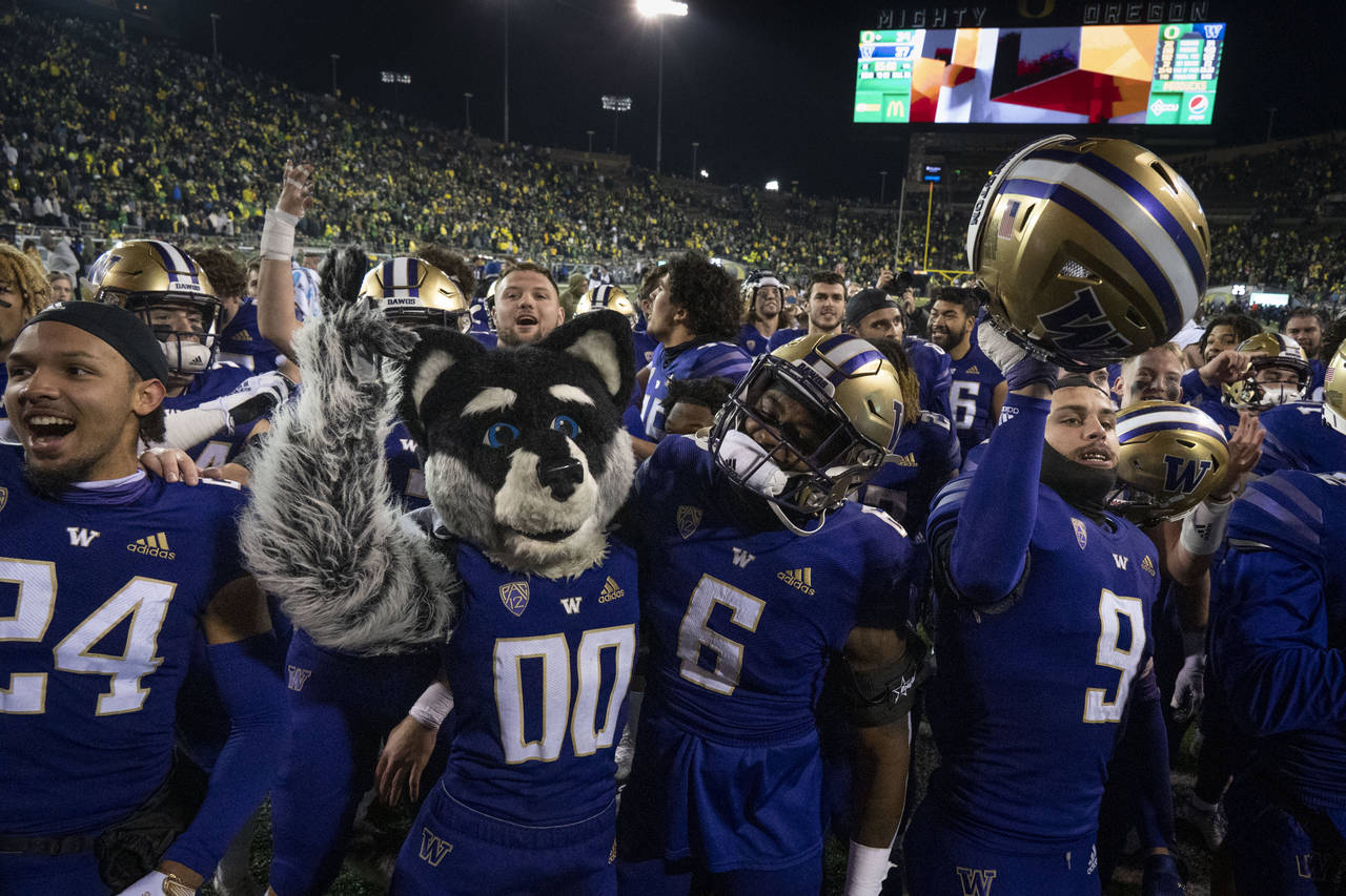 Washington players and their mascot celebrate after defeating Oregon in an NCAA college football ga...