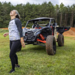 
              In this photo provided by Can Am Off-Road, Hailie Deegan laughs next to Can-Am Maverick X3 on the track she carved into the front yard of her first home, in Denver, N.C., on Aug. 30. 2022. Deegan is the only full-time female driver at the NASCAR national level but her future is unclear after Friday night’s Truck Series season finale. (Can Am Off-Road via AP)
            