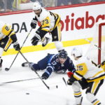 
              Winnipeg Jets' Michael Eyssimont attempts to pass the puck as Pittsburgh Penguins' Jeff Petry (26), Pierre-Olivier Joseph (73) and Josh Archibald (15) defend in front of Penguins goaltender Tristan Jarry (35) during first-period NHL hockey game action in Winnipeg, Manitoba, Saturday, Nov. 19, 2022. (John Woods/The Canadian Press via AP)
            