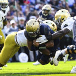 
              Navy quarterback Xavier Arline (7) runs the ball and dives into the end zone for a touchdown against two Notre Dame defenders during the first half of an NCAA college football game, Saturday, Nov. 12, 2022, in Baltimore. (AP Photo/Terrance Williams)
            