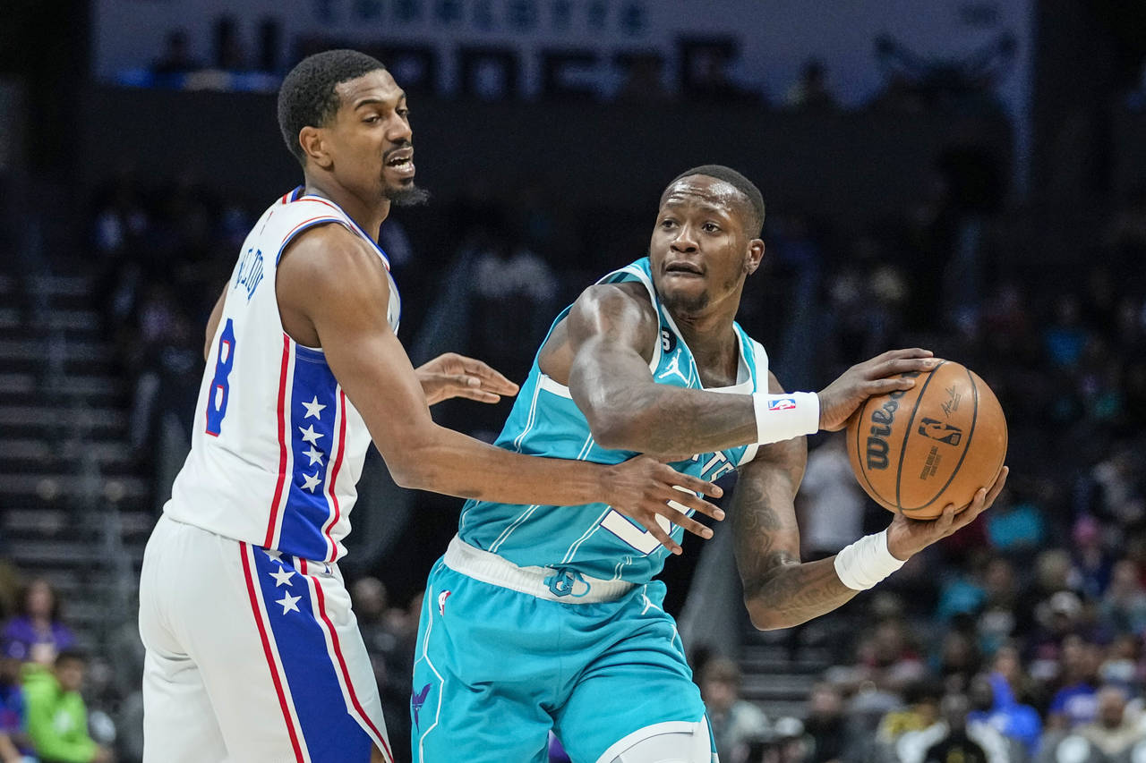 Charlotte Hornets guard Terry Rozier, right, looks to pass around the defense of Philadelphia 76ers...
