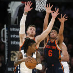 
              Memphis Grizzlies guard Ja Morant, with the ball, is defended by New York Knicks center Isaiah Hartenstein, left, and guard Quentin Grimes (6) during the first half of an NBA basketball game, Sunday, Nov. 27, 2022, in New York. (AP Photo/John Munson)
            