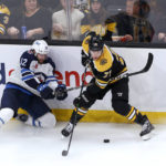 
              Boston Bruins left wing Taylor Hall (71) makes a play for the puck as Winnipeg Jets center Jansen Harkins (12) crashes into the boards during the third period of an NHL hockey game Thursday, Dec. 22, 2022, in Boston. (AP Photo/Mary Schwalm)
            